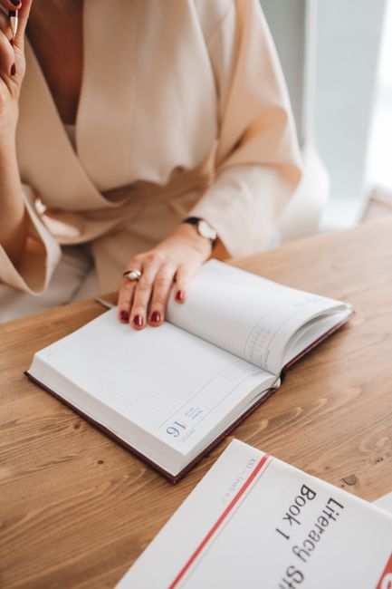 Persona escribiendo notas en un cuaderno junto a una laptop sobre una mesa de trabajo